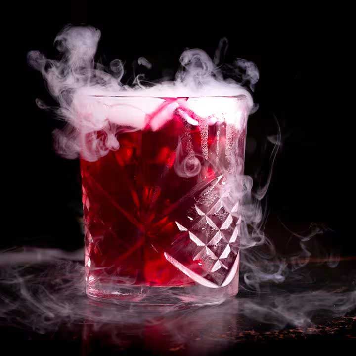 COCKTAIL OF RED DEATH - A bright vibrant cocktail made with 100-proof vodka, cherry herring, benedictine liquor, lime juice, pineapple juice, and bitters.