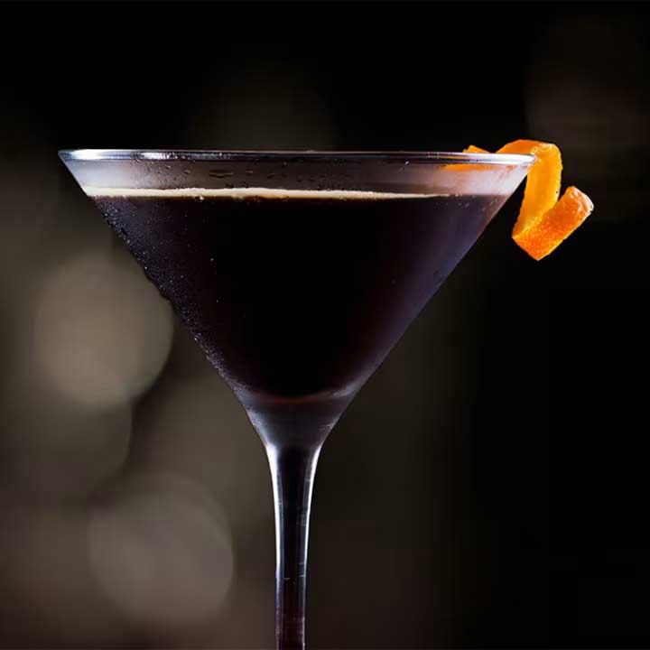 THE NEVERMORE - A black and gold cocktail fueled by orange peach blossom vodka, lime juice, and secret spices.